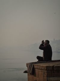Man photographing by sea against sky
