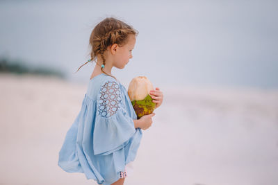 Side view of young woman holding globe against white background