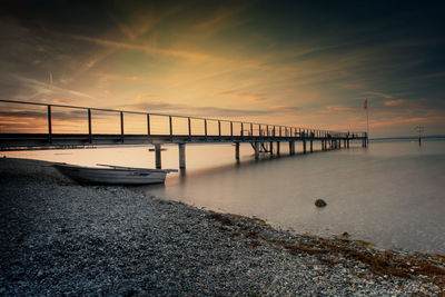 Pier in sea against sky during sunset