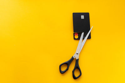 Cut black credit card on yellow background, finance concept