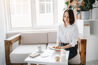 Young woman sitting with coffee cup on table