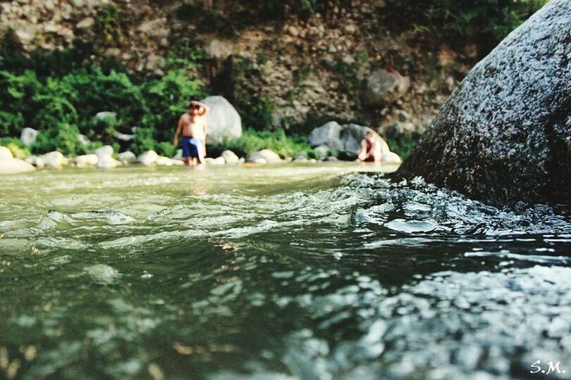 water, leisure activity, lifestyles, full length, waterfront, rock - object, motion, men, river, nature, standing, selective focus, day, wet, walking, outdoors, casual clothing, rock