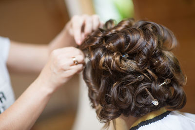 Cropped hands of hairdresser styling female customer at hair salon