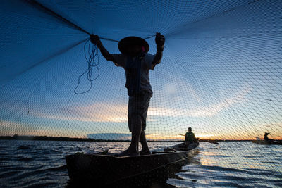Man with fishing net during sunset