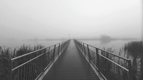 View of footbridge in foggy weather against sky