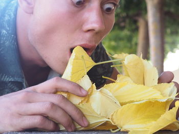 Close-up of young man with yellow autumn leaves