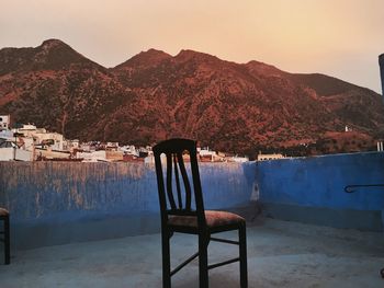 Empty chairs in front of rocky mountains against clear sky