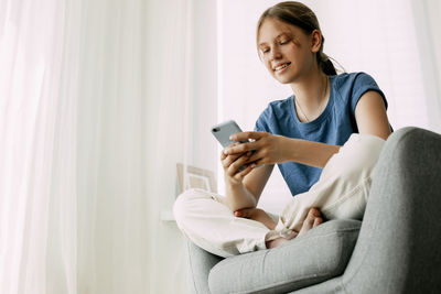 Young woman using mobile phone at home