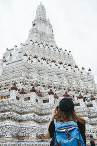 Rear view of woman standing outside temple against building