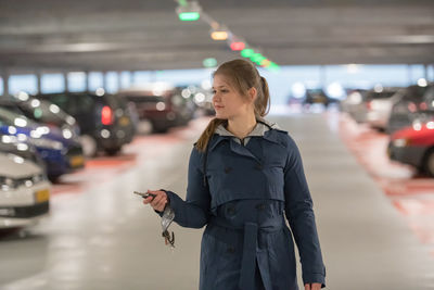 Full length of woman using remote key to lock car in parking lot