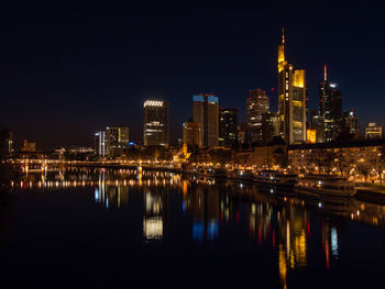 Illuminated buildings in city against clear sky at night