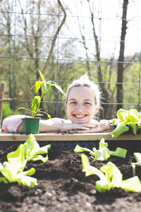Smiling woman leaning on raised bed in yard