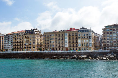 Buildings by sea against sky