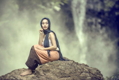 Portrait of young woman sitting on rock