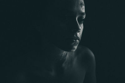 Close-up of thoughtful woman with face paint against black background