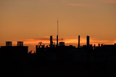 Silhouette of factory against sky during sunset