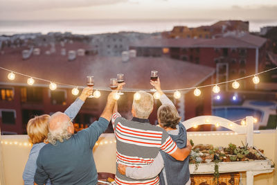 Rear view of senior couples holding wineglasses on building terrace