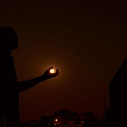 Optical illusion of silhouette hand holding moon at night