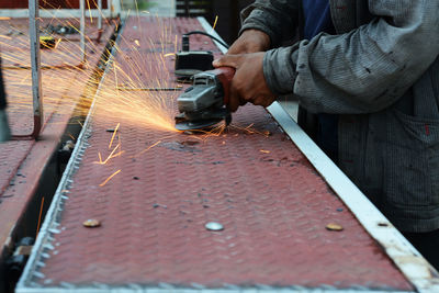 Midsection of man working on metal