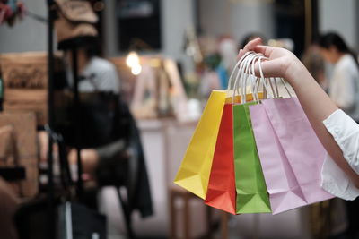 Cropped hand of woman holding shopping bags