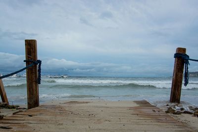 Pier on sea against cloudy sky