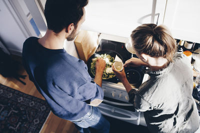 High angle view of man and woman cooking pasta in kitchen at home