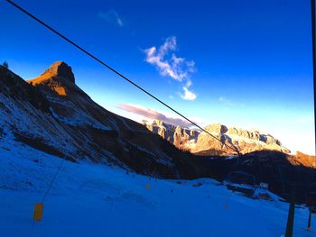 Low angle view of snow covered mountain against blue sky