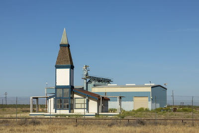 House on field against clear blue sky