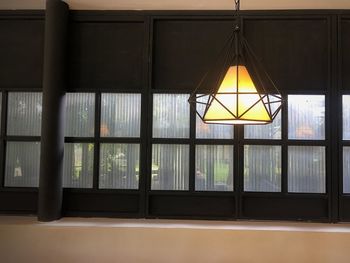 Illuminated pendant lights hanging on glass window at home
