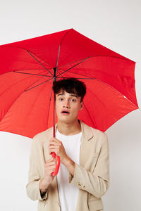 Portrait of man holding umbrella against white background