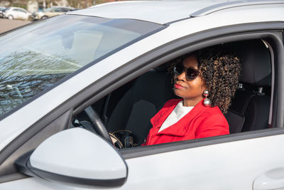 Pretty african american woman in a car doing makeup while standing in a traffic