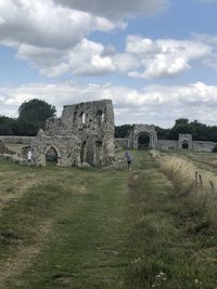 Old ruins on field against cloudy sky