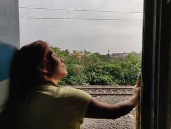 Rear view of woman looking through window