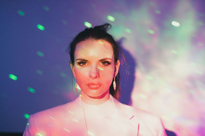 Portrait of beautiful young woman against illuminated background