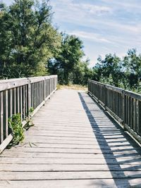 Footpath by footbridge against sky