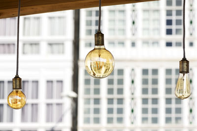 Low angle view of illuminated light bulbs hanging from ceiling