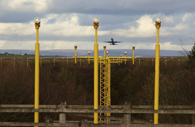 Metallic structure by fence against sky