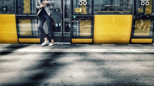 Low section of woman walking by train at railroad station