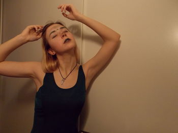 Portrait of young woman standing against wall