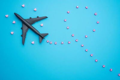 Travel valentine day concept flat lay design with airplane and heart shape beads on blue background 