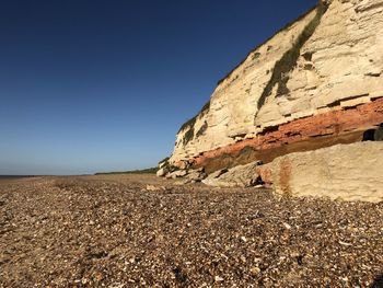 Rocks on land against clear blue sky