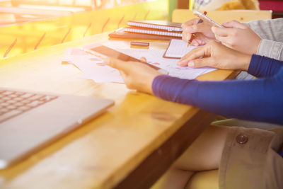 Midsection of woman reading book on table