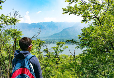 Rear view of boy standing against trees