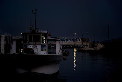 Sailboats moored at harbor against sky at dusk