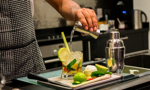 Midsection of bartender preparing cocktail