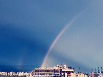 Rainbow over city against blue sky