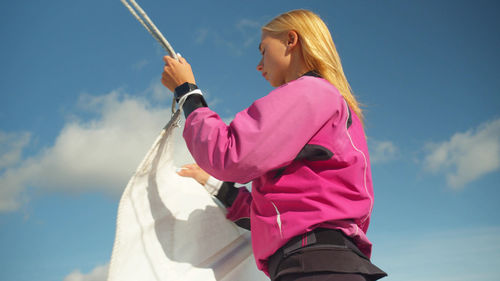 Low angle view of woman holding pink umbrella against sky