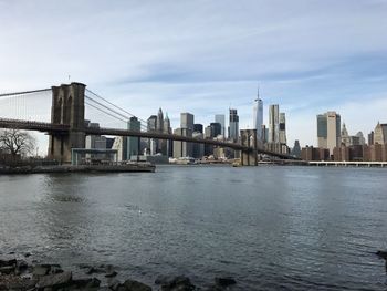 Bridge over river in city against sky