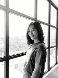 Portrait of young woman standing by window