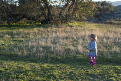 Rear view of girl standing on grassy field